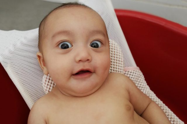 Facial expressions of a baby while taking bath.