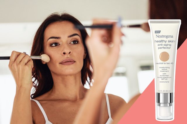 A woman applies makeup with a brush in front of a mirror; Neutrogena Healthy Skin anti-aging perfector tube displayed beside her.