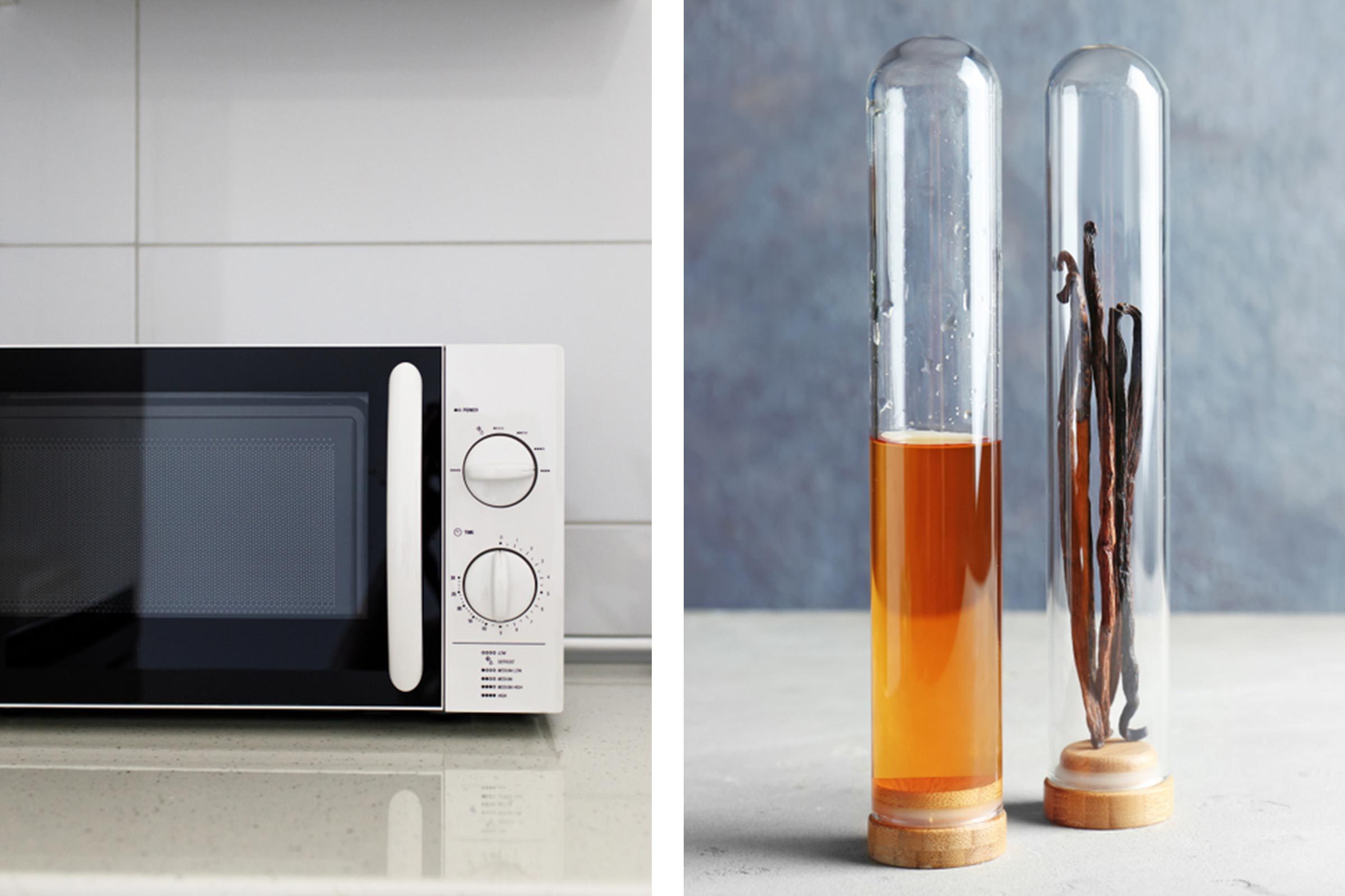 Microwave sits on a kitchen counter, next to test tubes containing amber liquid and dried vanilla pods, against a tiled and textured background.