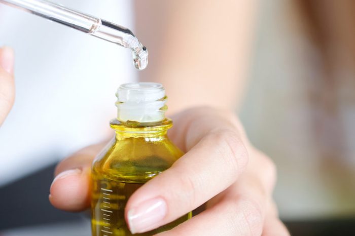 hands of a beautiful woman Dropping serum collagen moisturizer of face into clear yellow bottle soft light background. Protector skin Treatment facial essence oil, Vitamin C. Beauty and spa Con