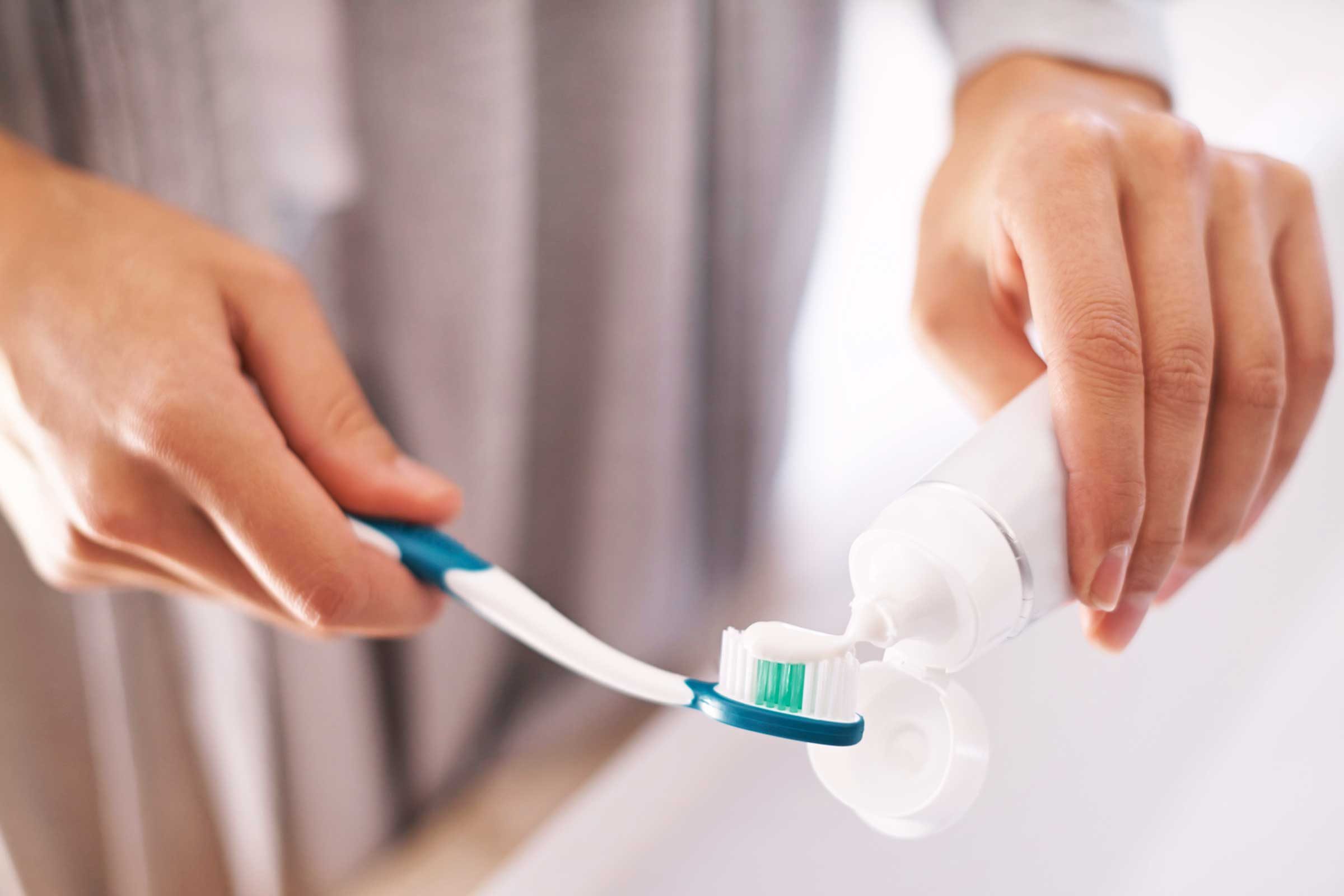 person putting toothpaste on their toothbrush