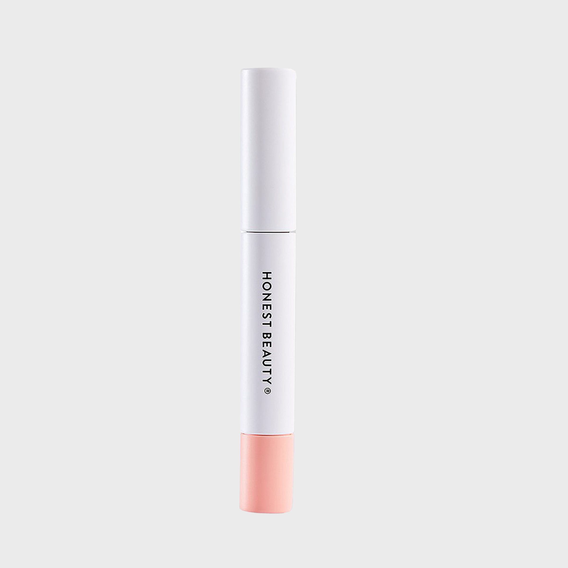 A dual-ended makeup stick stands upright; one end is white with text "HONEST BEAUTY," the other is pink, set against a plain background.