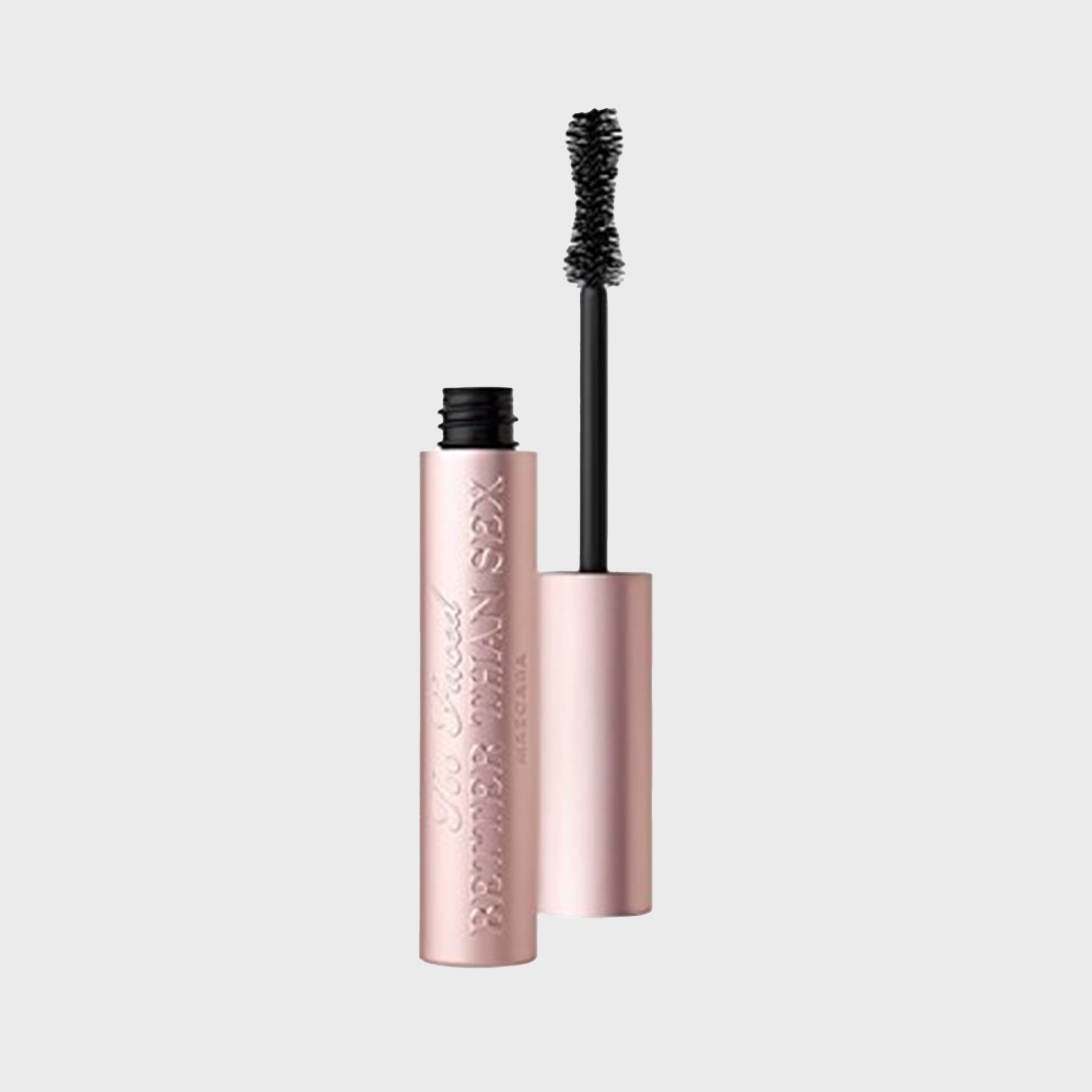 A pink mascara tube with an open wand, featuring embossed text on its body, sits against a plain grey background.
