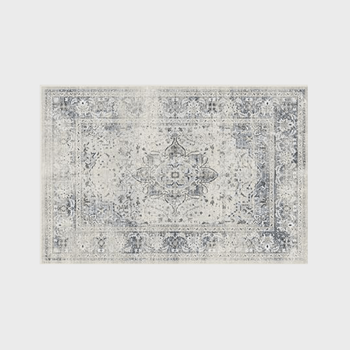 Decorative rug displaying intricate floral patterns, featuring a central medallion and bordered design, set against a light gray background.