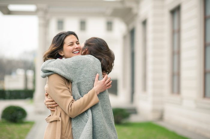 Two girls hug on the sidewalk. Feel joyfull and happy together.