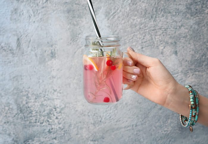 Female hand with jar of fresh lemonade on textured background
