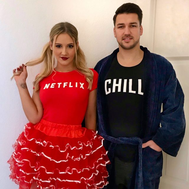 Two people pose indoors; one wears a 