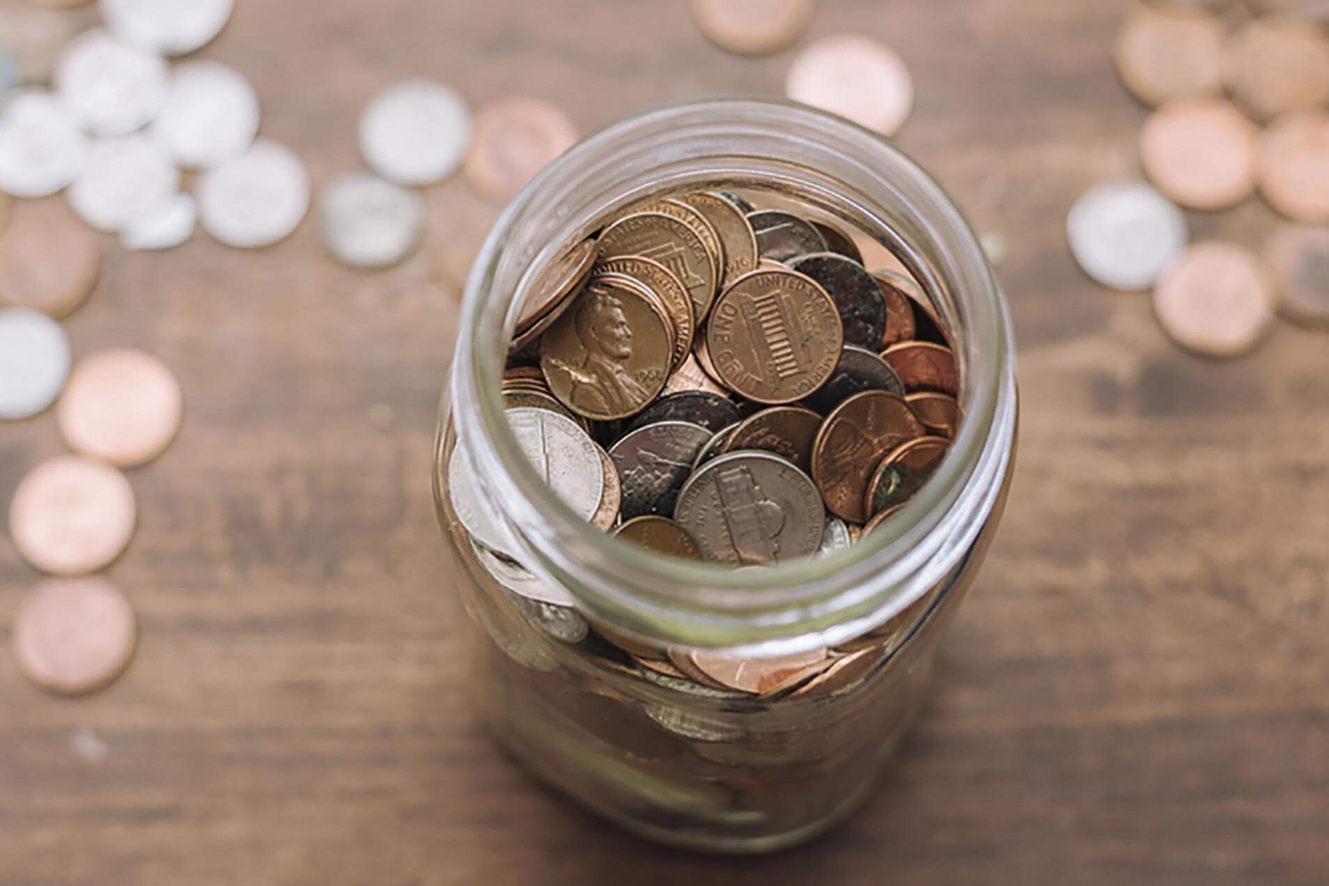 coin jar filled with savings on wood table