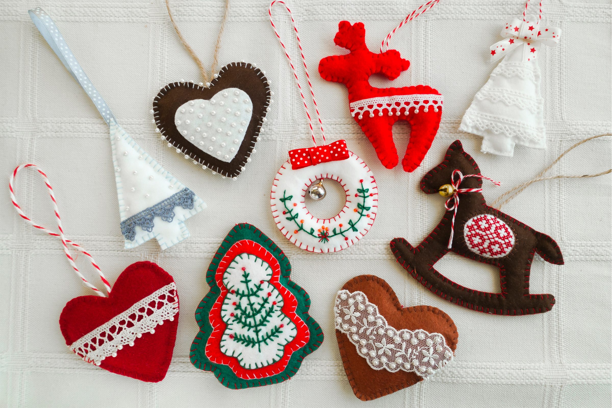  felt mand made decorations (wreath, rocking horse, christmas tree) on a white background, tablecloth