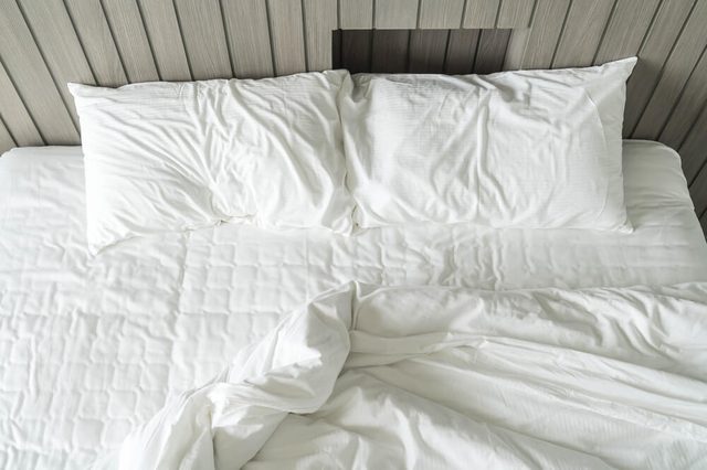 rumpled bed with white messy pillow decoration in bedroom interior