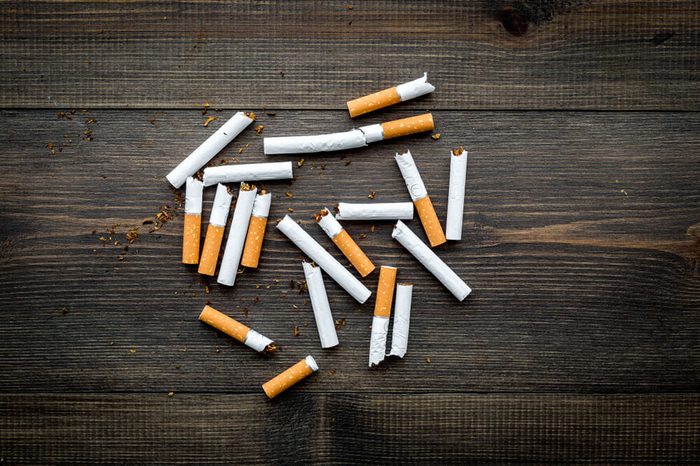 Tobacco. Scattered cigarettes on dark wooden background top view copy space
