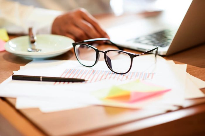 Close up of eye glasses on work desk with laptop at business workplace.