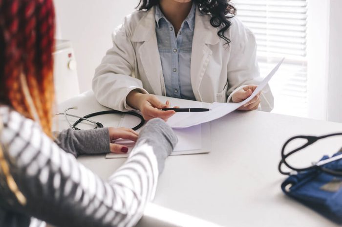 Doctor and patient are discussing about diagnosis. Medical doctor on white background holding a stethoscope, looking at medical form and taking notes.