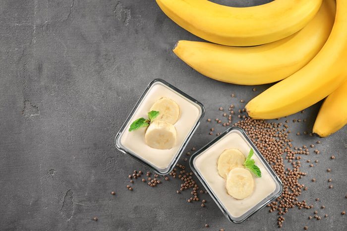 Bowls with delicious banana pudding on grey background