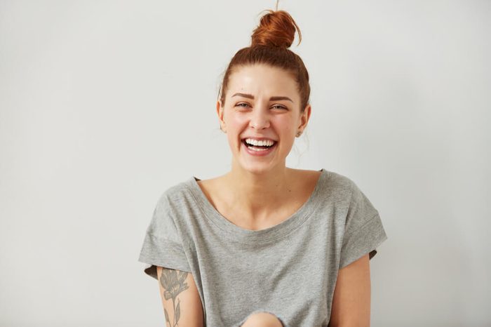 Happy woman Laughing. Closeup portrait woman smiling with perfect smile and white teeth looking laugh loudly isolated grey wall background. Positive human emotion facial expression body language.