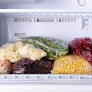 Frozen berries and vegetables in bags in freezer close up