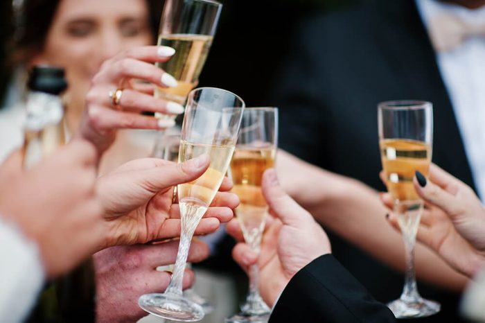 Wedding couple, bridesmaids and groomsmen drinking champagne outside.