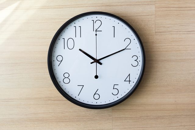 black and white clock on light wooden wall with shiny on the wall, ten past ten o'clockconcept : late appointment, late morning, wake up late,