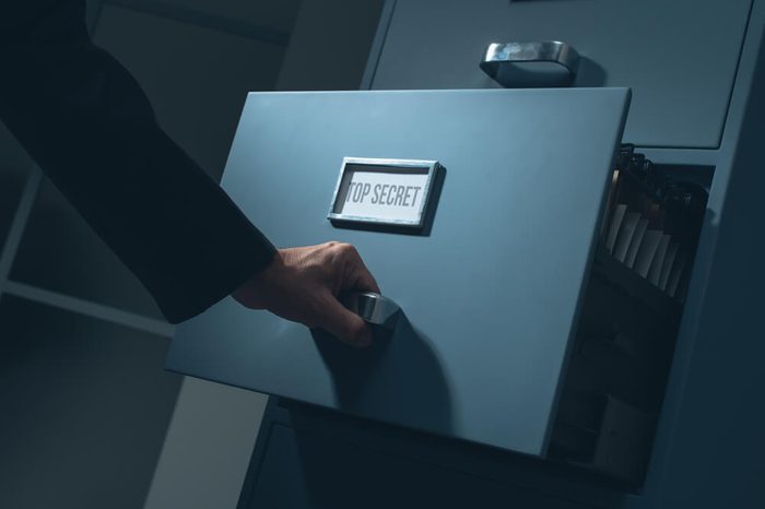 Office worker searching top secret confidential information in the office late at night, data theft and security concept