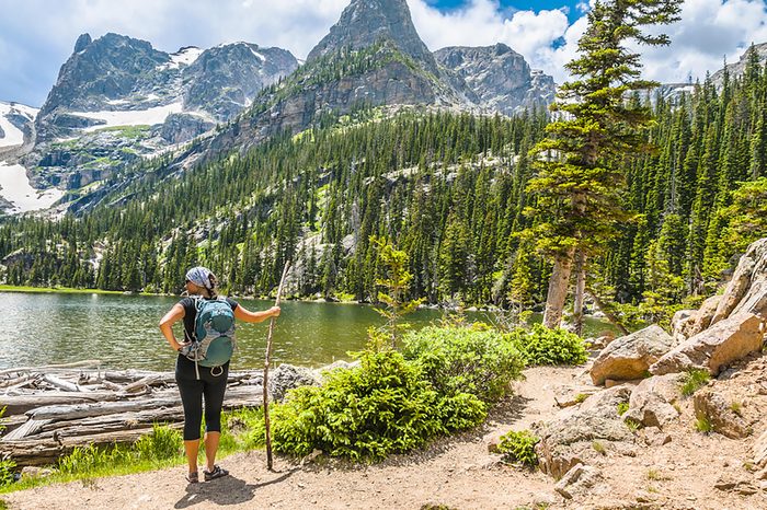 Young attractive female enjoying stunning view at lake Odessa with notchtop peak in rocky mountain national park colorado