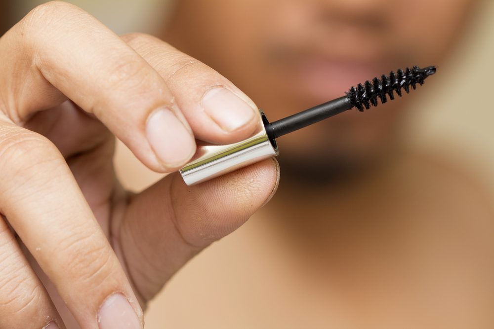 mascara brush, holding a mascara brush.