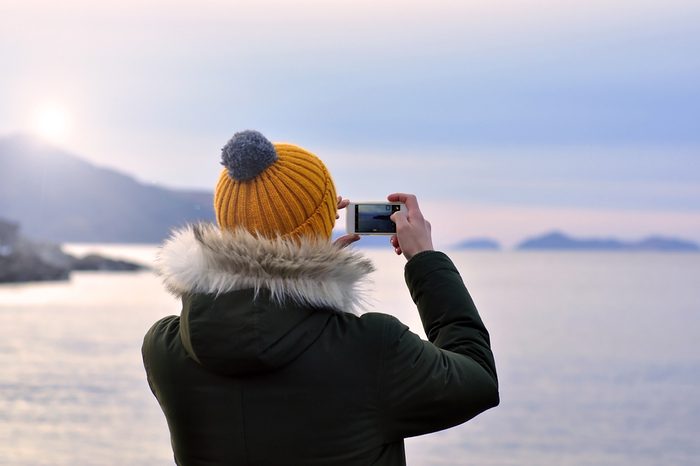 A man taking a picture by phone in Oslo during a cold gray winter Day