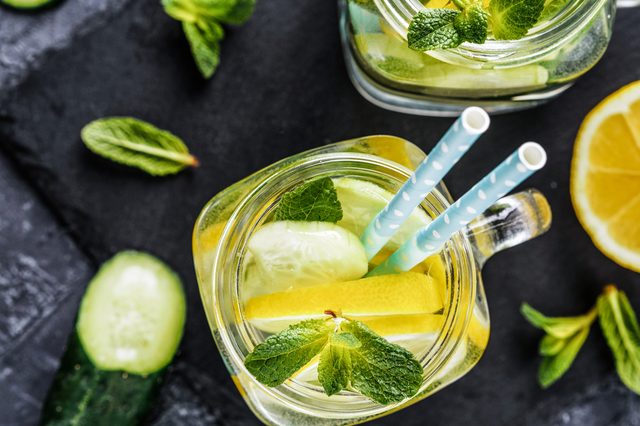 Above view of two mason jar with detox water on dark concrete background. Summer drink with cucumber, lemon and mint. Copy space. Top view or flat lay