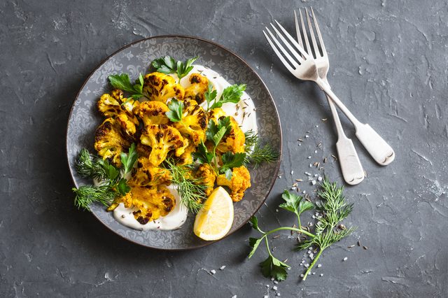 Roasted turmeric cauliflower with greek yogurt dressing. Delicious healthy snack on a dark background, top view    