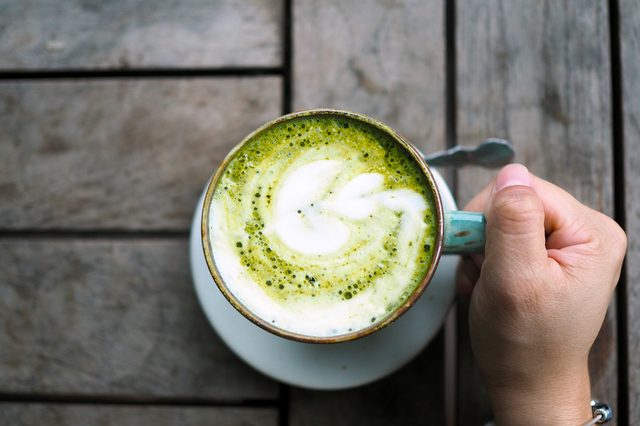 A ceramic cup of Japanese matcha latte with beautiful latte art on wooden table. Selective focus.