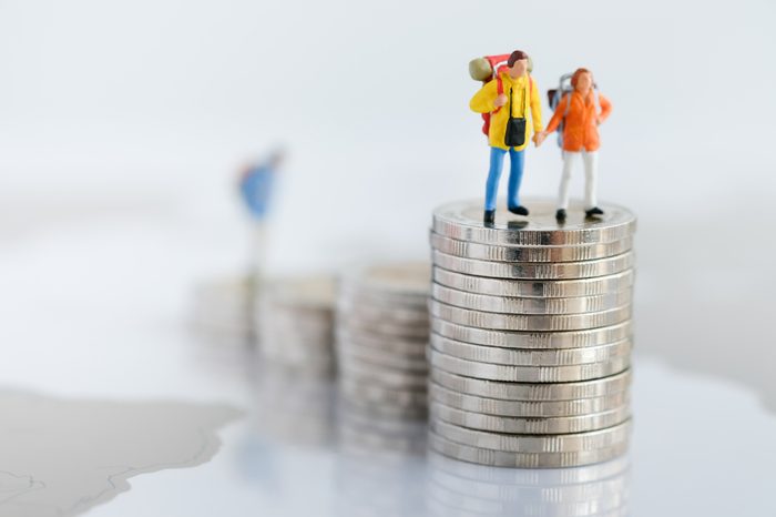 Miniature people: Two backpacker standing on rows of stack coins using as background Money, Financial, Business Growth and travel concept,