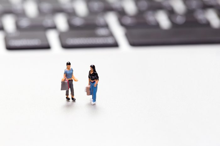 Miniature shopper with shopping bag on a laptop keyboard. Online shopping concept.