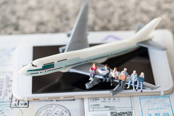 Travel Concept. Group of traveler siting and waiting on airplane wing on smart phone and passport with immigration stamps