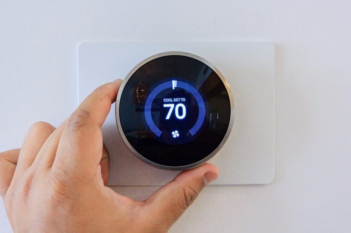 hand adjusting air conditioner button at 70 degree Fahrenheit in the apartment for comfortable
