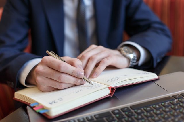 Office worker writing notes in planner book