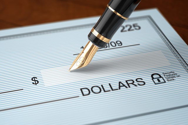 Writing a check with an old fashioned fountain pen on a wooden table