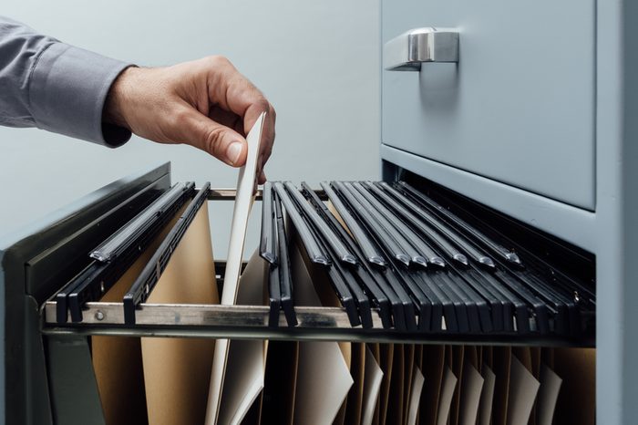 Office clerk searching for files into a filing cabinet drawer close up, business administration and data storage concept