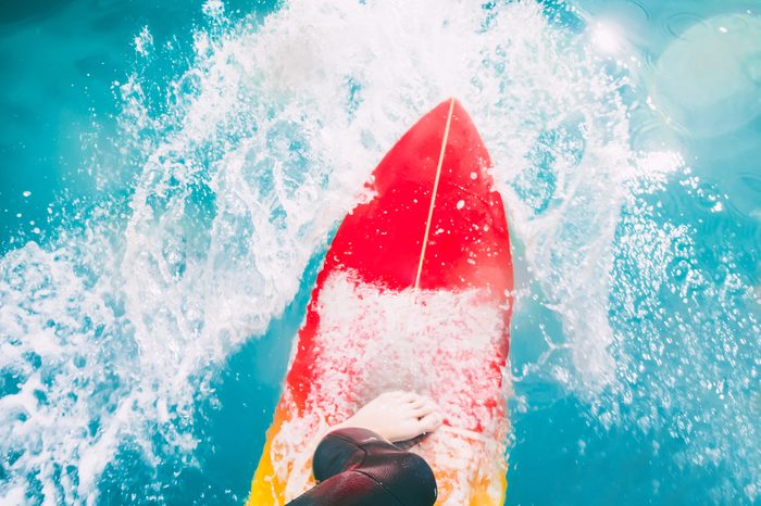 Surfer on red surfboard ride on blue wave. Surfing in ocean