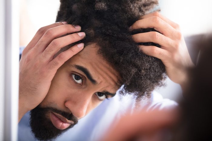 Close-up Of A Young Man Examining His Hair