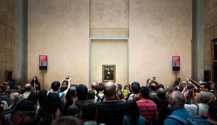 PARIS, FRANCE - JUNE 18 , 2014 : A many of visitors take photos of "Mona Lisa" , by Leonardo DaVinci's at the Louvre Museum, june 18, 2014 in Paris, France.