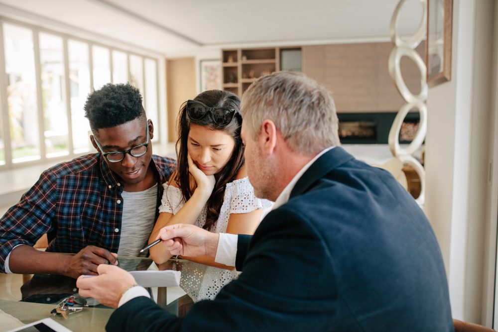 Financial consultant explaining every detail of mortgage to couple. Realtor explaining lease agreement or purchase contract to couple in an apartment.