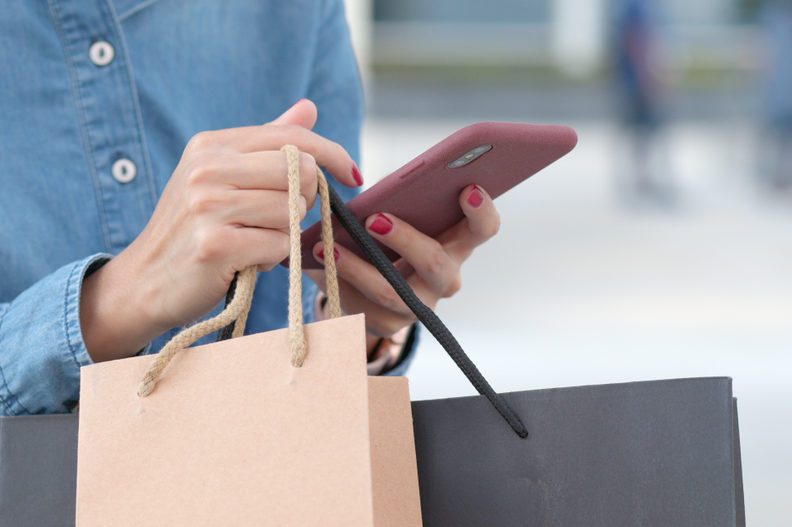 Woman use of mobile phone for shopping with holding shopping bag 