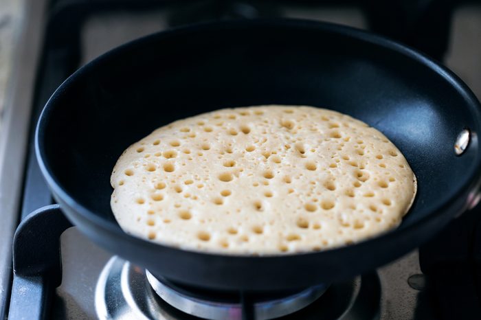 Making american pancakes on frying pan in kitchen interior, preparation breakfast food, nobody