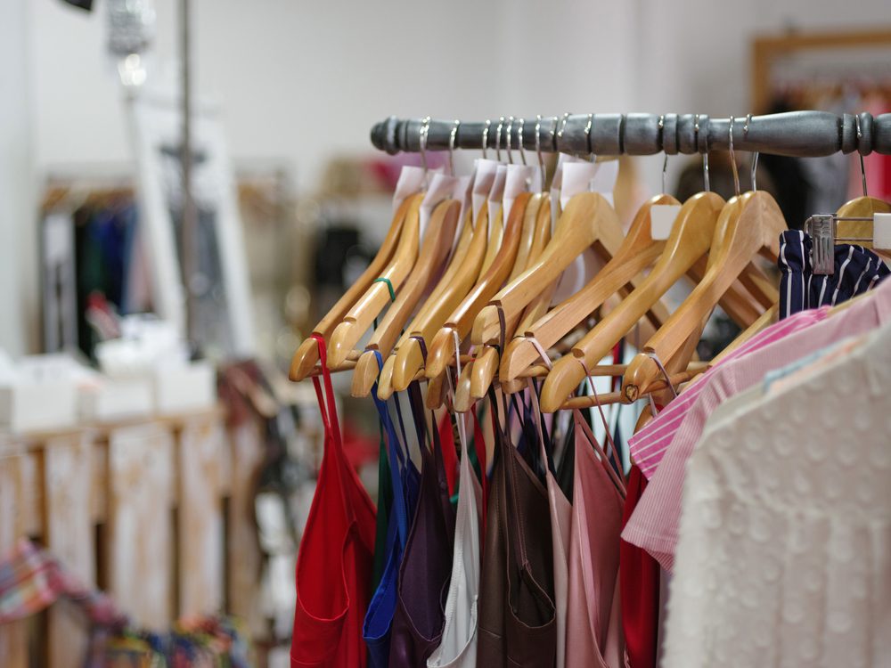 A big assortment colorful clothes for women on a shop background. Various fashionable color shirts and dresses in a expensive boutique. Luxury and stylish garment on hangers. Fashion concept.