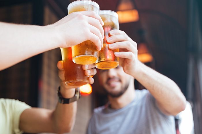 Happy male friends clinking with beer mugs in pub