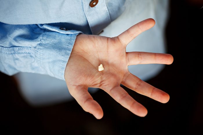 Kids Hand with one milk tooth. First tooth lost.