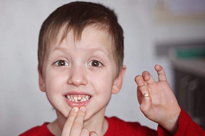 Portrait cute little Boy shows the First dropped-out milk Tooth.