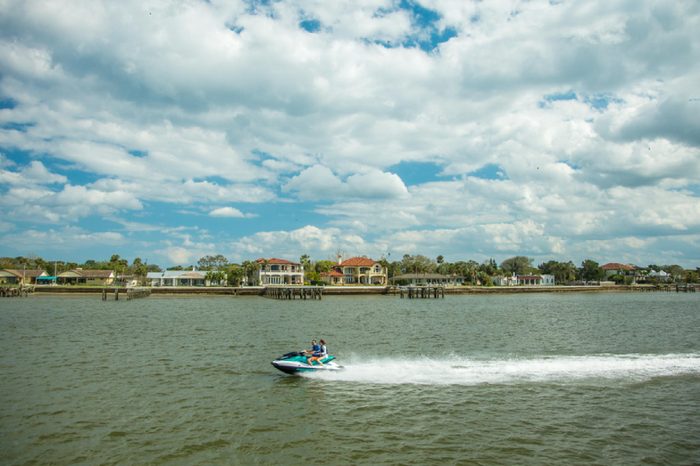St Augustine, Florida - 2/27/2018: Homes and other buildings on the shoreline that border the harbor at St Augustine, Florida. A speeding personal watercraft in forgeround.