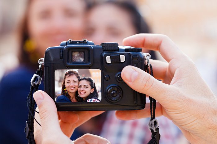 Happy beautiful smiley girlfriends being photographed by a man.