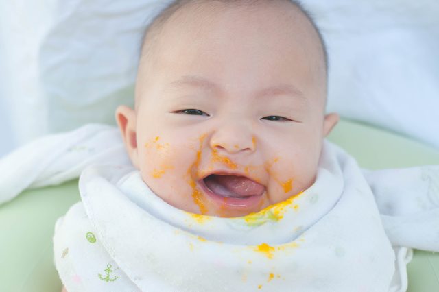 Cute happy smiling Asian baby infant feeding