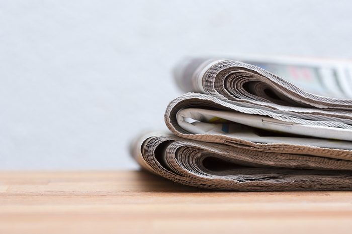 Pile of newspapers on a wooden table.